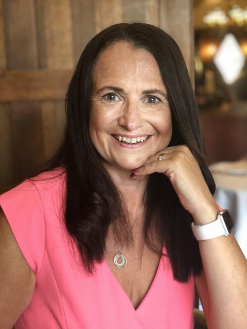 Image of a woman with brown hair, smiling, wearing a pink top